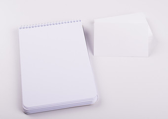 White color cards next to notebook on white background. Isolated. Mockup.