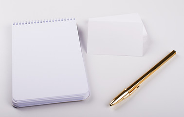 White cards next to notebook and golden pen on white background. Isolated. Mockup.