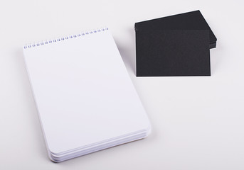 Black cards next to notebook on white background. Isolated. Mockup.