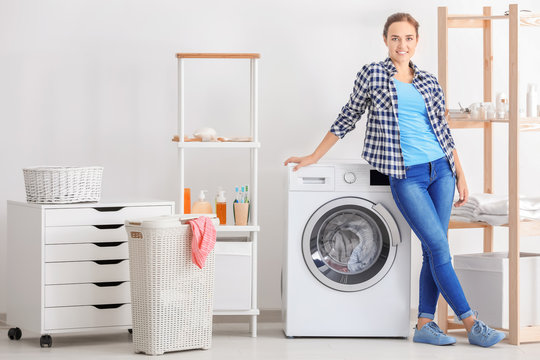 Young Woman Near Washing Machine In Laundry Room