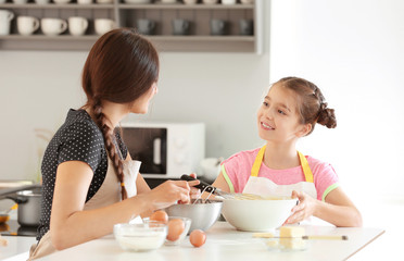Mother and daughter preparing dough indoors