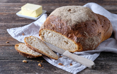 Frisch angeschnittenes rundes Landbrot auf Leinentuch und Holztisch