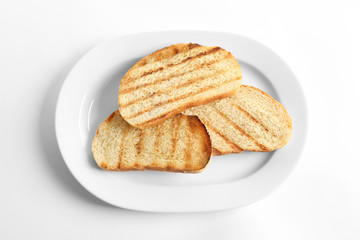 Plate with toasted bread on white background