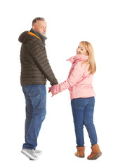 Mature couple in warm clothes walking on white background