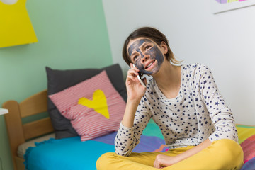 Always has time for her bast friends. Teenage girl with face mask using mobile phone in her room