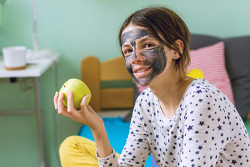 Teenage girl with face mask holding apple