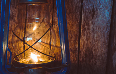 Kerosene lamp illuminates the old wooden wall