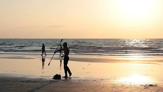 Muscular man spinning pole on the beach. 