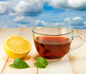 cup with tea, lemon, mint leaves against the sky close-up