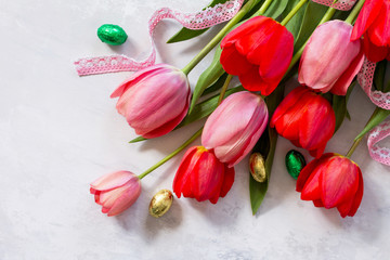 Spring concept. Colorful Easter background bouquet of tulips with colored eggs on a concrete background with copy space.