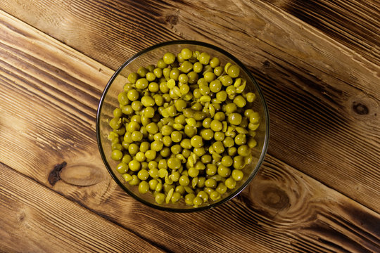 Canned green peas in glass bowl on wooden table