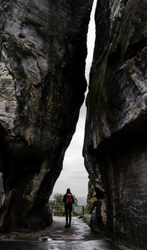 Eine Wanderin durchschreitet ein Felsmassiv in der Sächsischen Schweiz
