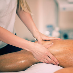 Fototapeta na wymiar Leg massage. Physical therapyst massaging leg of young male athelete
