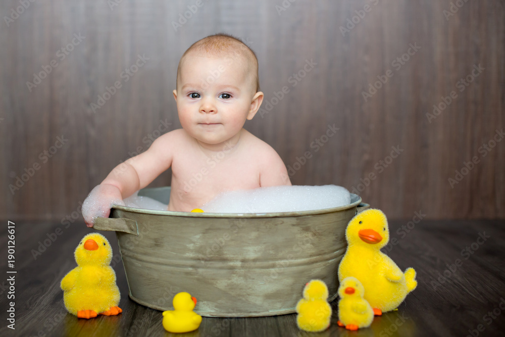 Canvas Prints Cute baby playing with rubber duck while sitting in metal basin