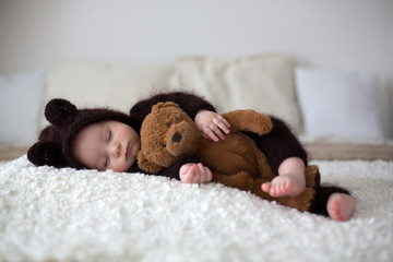 Sweet little baby boy, dressed in handmade knitted brown soft teddy bear overall, sleeping cozy