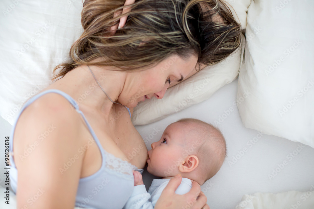 Sticker Young mother breastfeeds her baby, holding him in her arms and smiling