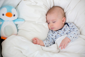 Sick child boy lying in bed with a fever, resting at home