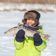 Boy fishing with rod on river in winter.