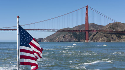 View towards the northern tower of Golden Gate Bridge, with an American flag in the foreground waving in the wind, from a ferryboat connecting Sausalito to San Francisco, California, USA