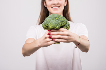 Fototapeta na wymiar Close up of a smiling woman showing broccoli isolated over white background. Health concept.