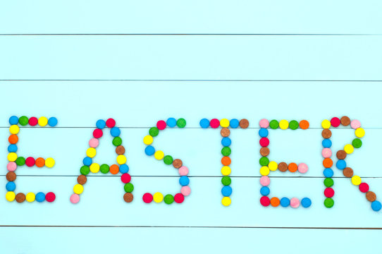 The word "EASTER" made from candies on a turquoise background