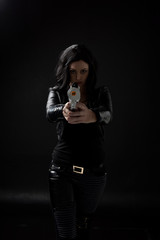 portrait of black haired girl wearing leather clothes, moody lighting on black background.