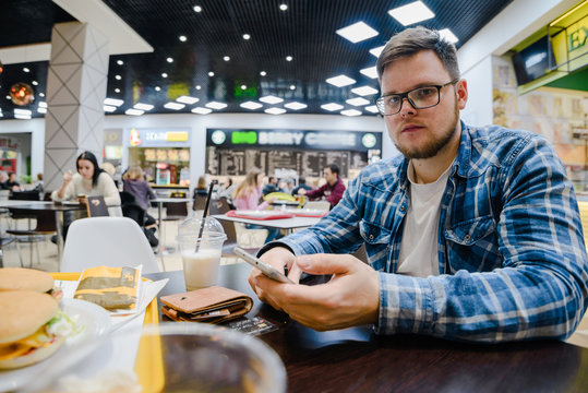 man searfing phone on background wallet with cup of milk shake on the table