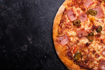 Top close up view of fresh hot baked pizza on dark wooden background with copy space available
