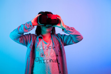 Amazed kid experiencing virtyal reality for the first time in studio on blue background