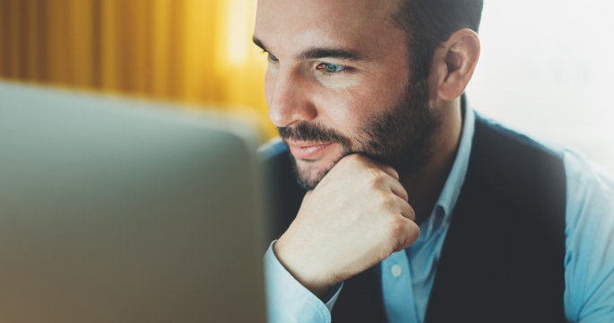 Bearded young businessman working on modern office at night. Consultant man thinking looking in monitor computer. Manager typing on keyboard in coworking workplace, startup project concept in studio