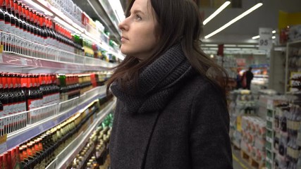 Young woman buying dairy or refrigerated groceries at the supermarket in the refrigerated section