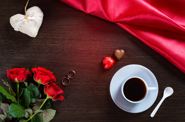 Happy Valentines Day romantic background with wedding rings, rose flowers, cup of coffee and chocolate candy