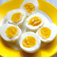 Halfs of three hard boiled eggs lying on a yellow plate.