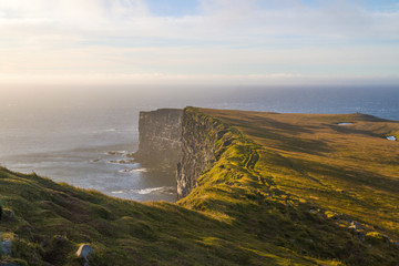 Wilderness of Latrabjarg bird cliffs during suggestive sunset light with ocean fog, Westfjords...