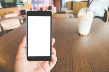 Hand holding black mobile smart phone with blank black screen in coffee shop cafe. technology and lifestyle concept.