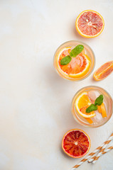 Cold refreshing drink with blood orange slices in a glass on a white concrete background. Top view, flat lay, copy space.