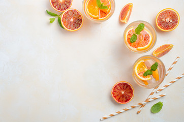 Cold refreshing drink with blood orange slices in a glass on a white concrete background. Top view, flat lay, copy space.