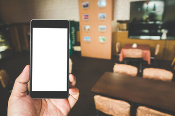 Hand holding black mobile smart phone with blank black screen in coffee shop cafe. technology and lifestyle concept.
