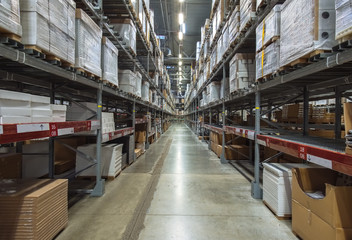 Large warehouse logistic or distribution center. Interior of warehouse with rows of shelves with big boxes