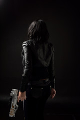 portrait of black haired girl wearing leather clothes, moody lighting on black background.
