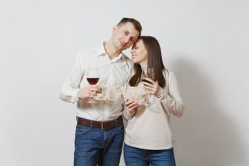 Young caucasian couple. Happy smiling man and woman in love in casual light clothes, jeans making toast, drinking from glasses of red wine isolated on white background. Copy space for advertisement.
