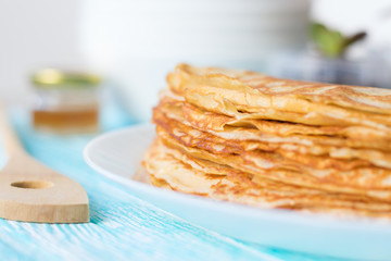 Thin russian pancakes on a plate on white wooden table. Shrove Tuesday. Healthy breakfast concept. Close up.