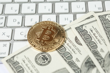 New virtual money Golden bitcoin coin and dollars on a white keyboard. Cryptocurrency. Business and Trading concept.
