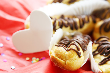 valentine's day concept, holiday greeting card, breakfast for lover: eclairs and hearts on red festive background