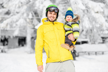 Portrait of a happy father with baby boy standing in winter spots clothes outdoors during the winter vacations