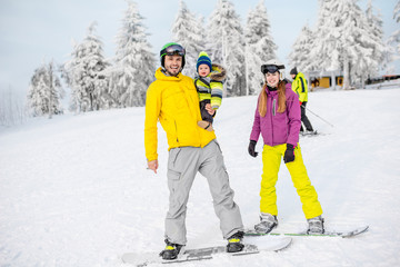 Portrait of a happy family with baby boy riding on the snowboards during the winter vacations on...
