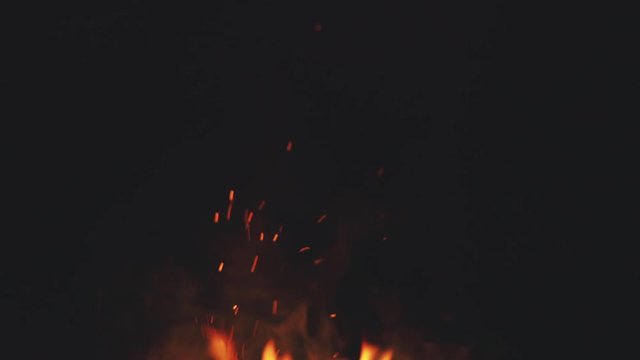 fire flames with sparks from campfire over black background
