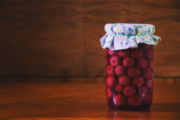 Preserved fruit in jar, compote of cherries. Homemade conserved fruits in glass on a wooden table. 