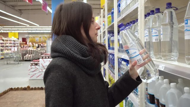 Close up portrait of a girl in supermarket choosing water