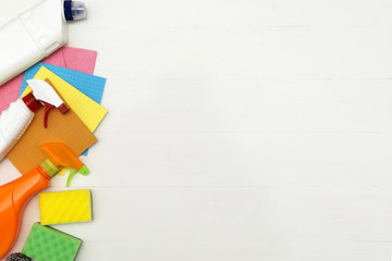 Cleaning concept with supplies on white wooden background